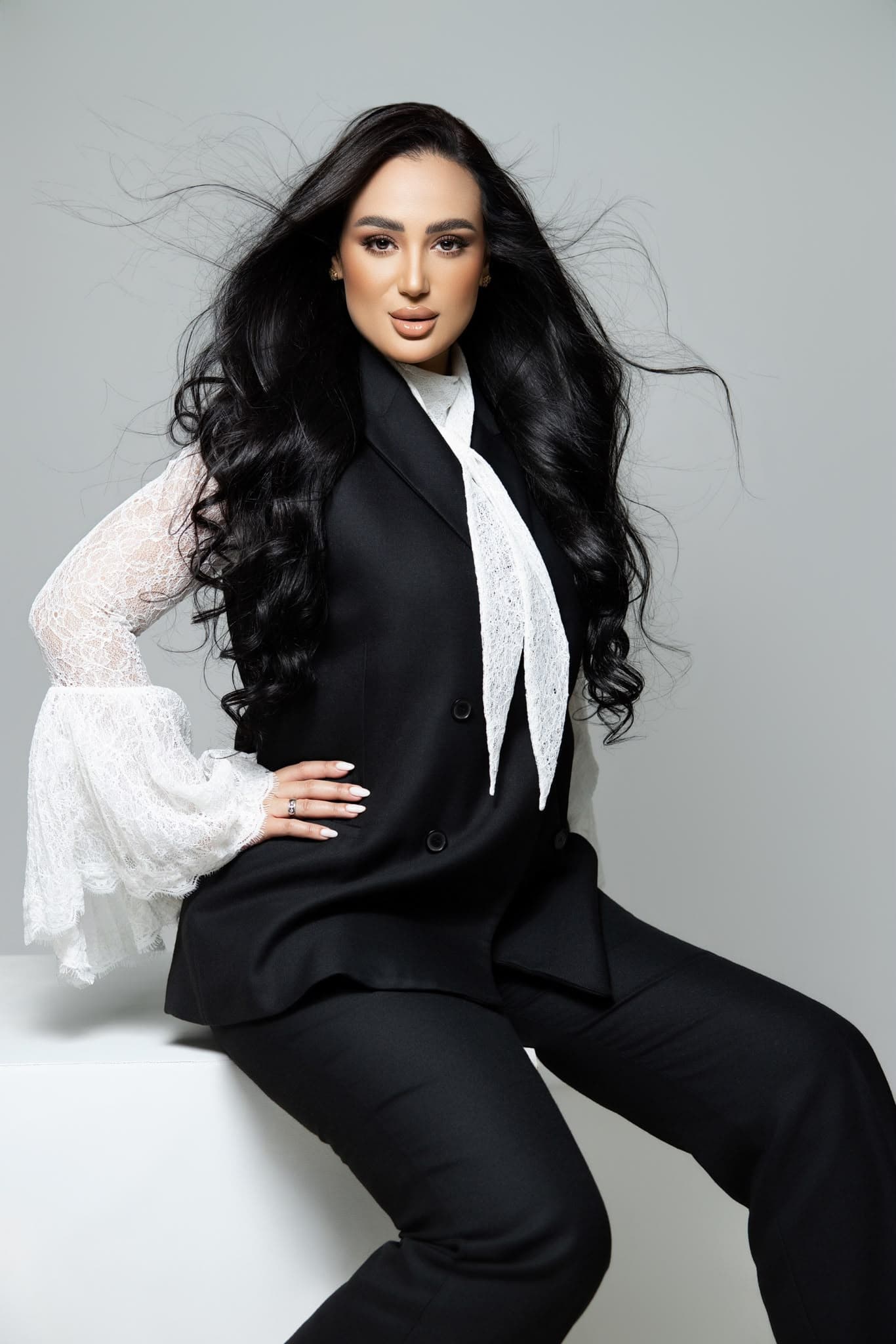 Ghada Arbi seated in her black suit studio portrait